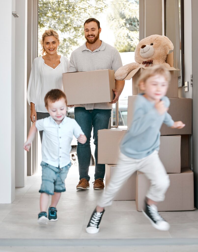 Happy family moving into new house. Excited children running into their new house. Family carrying